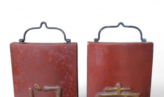 Two red leather-bound books with metal handles on a white background