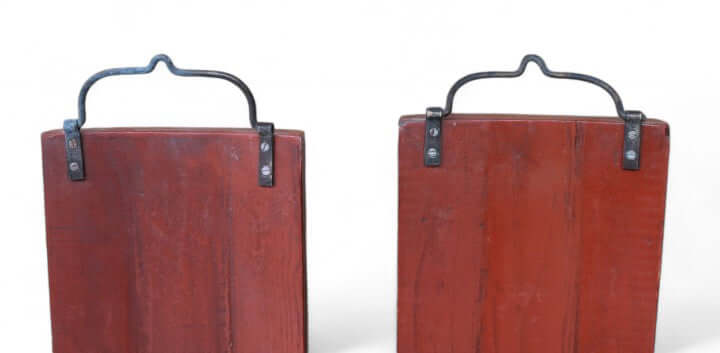 Two red suitcases with black handles on a white background
