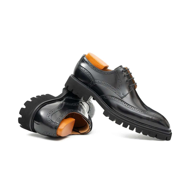 Black derby brogue shoes by DV DIVINCH, made of calfskin leather with intricate detailing and cushioned lug sole.