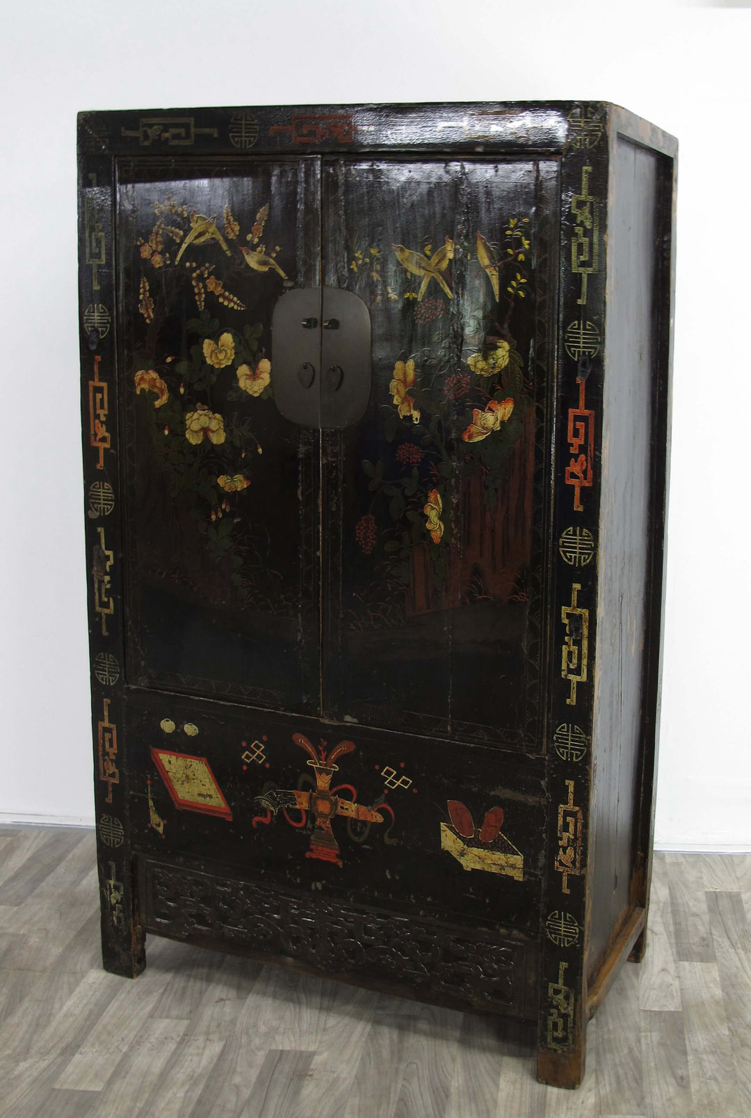Decorative black cabinet with gold and red designs on a white background