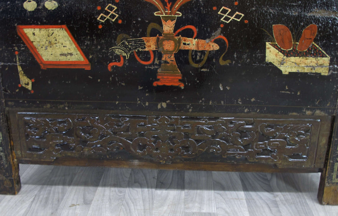 Decorative wooden panel with intricate carvings and painted elements on a black background.