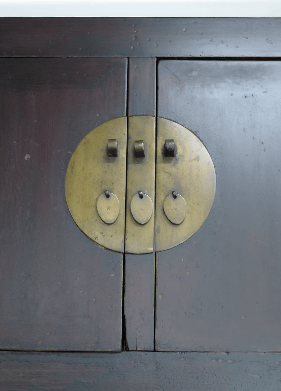 Close-up of a wooden cabinet with brass circular handles.