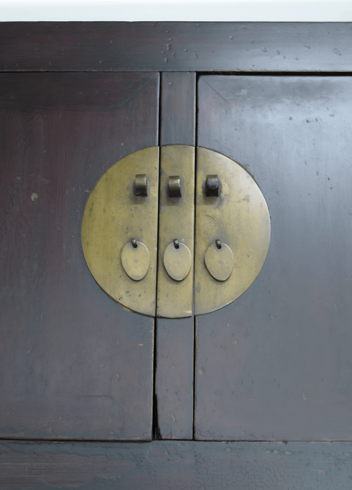 Close-up of a wooden cabinet with brass circular handles.