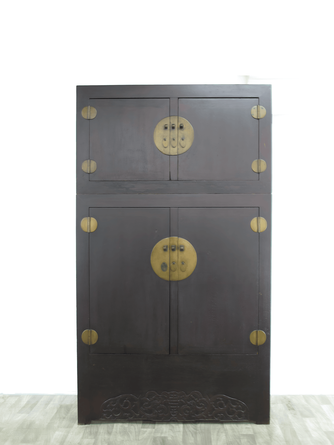 Dark wooden cabinet with brass circular handles on a white background