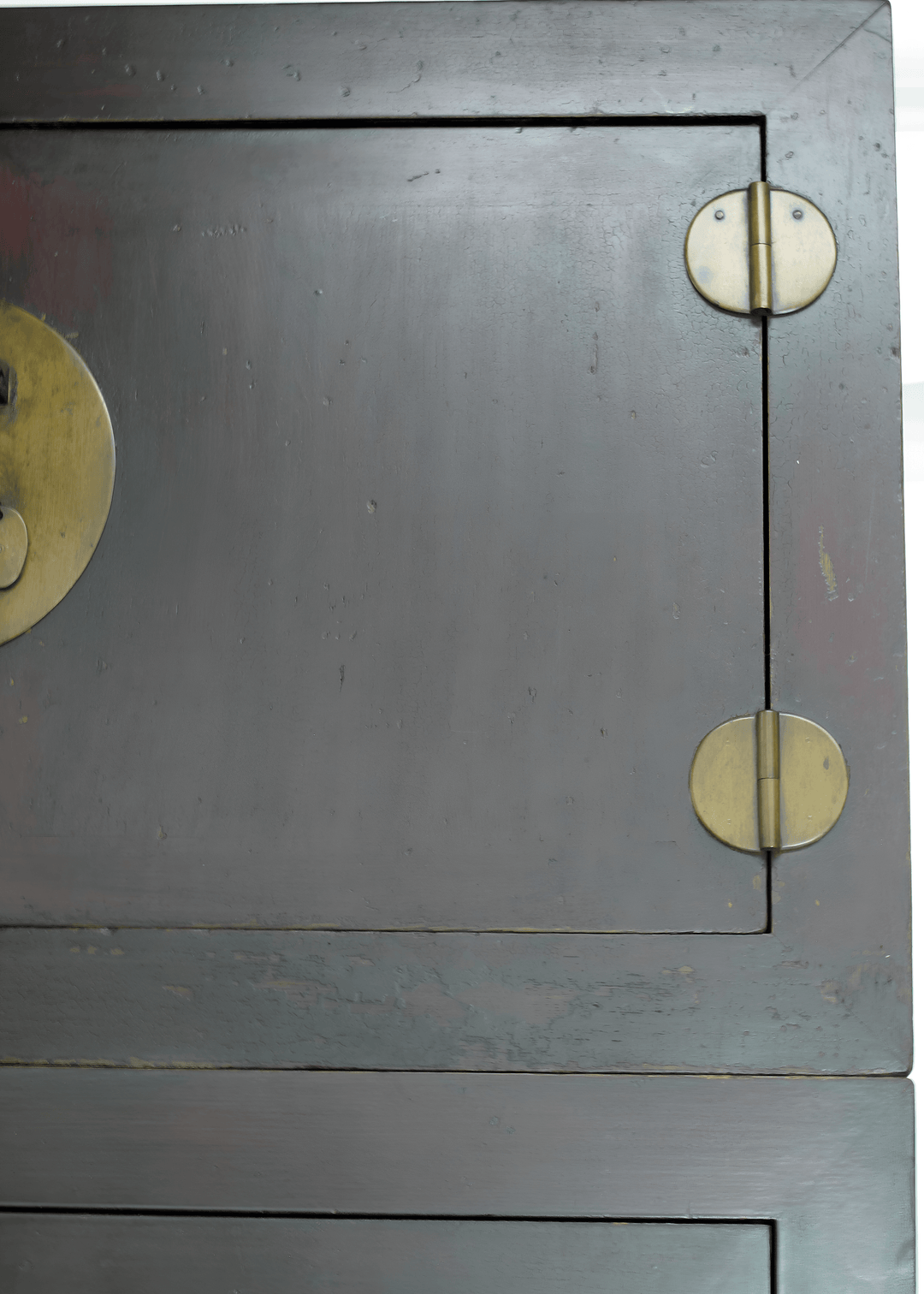 Close-up of a wooden cabinet with brass handles and hinges.
