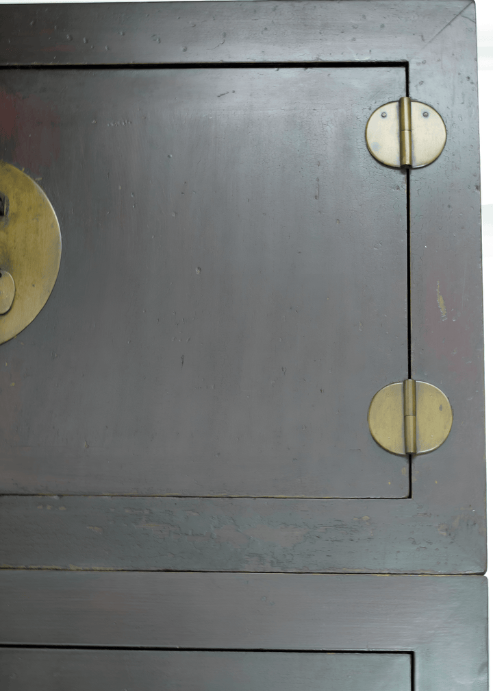 Close-up of a wooden cabinet with brass handles and hinges.