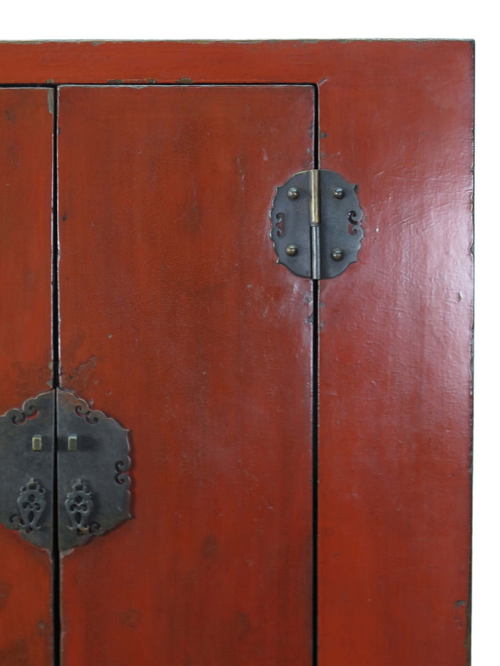 Close-up of a red wooden cabinet with metal handles and hinges.