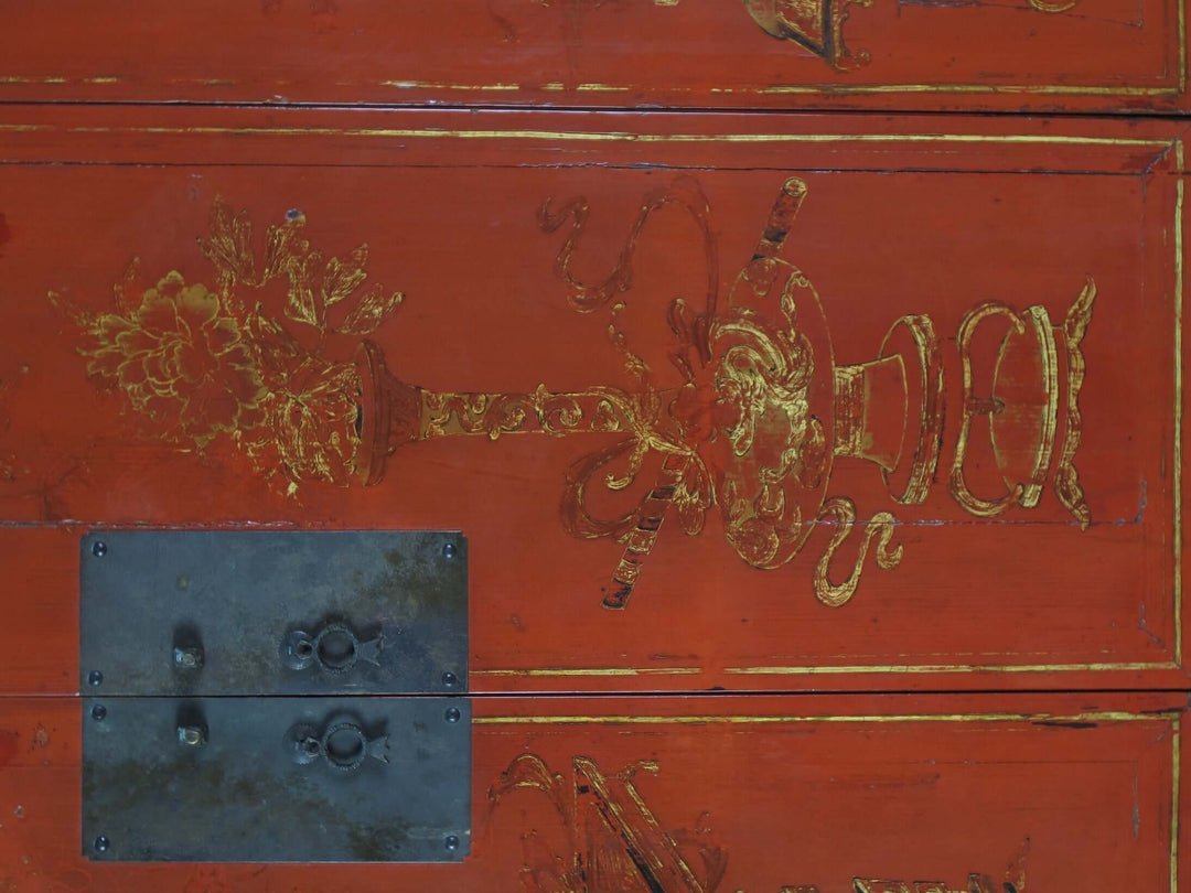Red wooden chest with gold decorative elements and a metal handle.