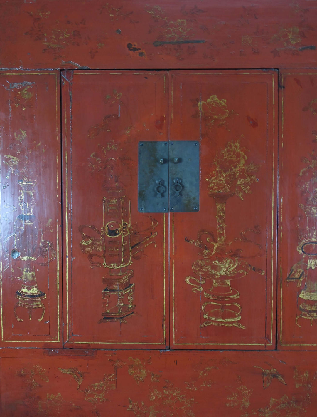 Red wooden cabinet with gold intricate carvings and a blue lock.