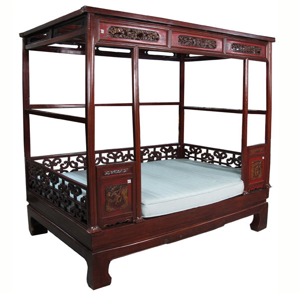 Traditional wooden bed with intricate carvings on a white background