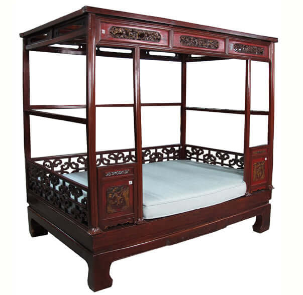 Traditional wooden bed with intricate carvings on a white background
