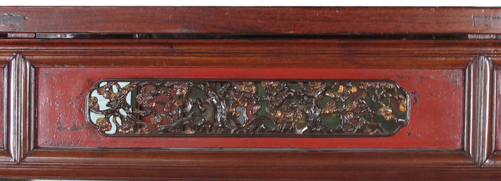 Decorative wooden panel with intricate carvings and a red background