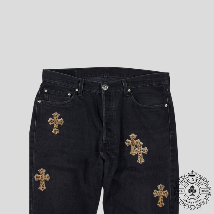 Black jeans with gold cross patches on a light gray background
