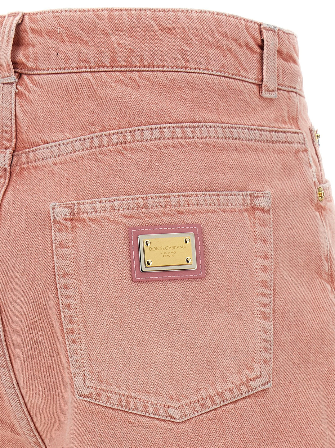 Close-up of a pink denim pocket with a brand label on a white background