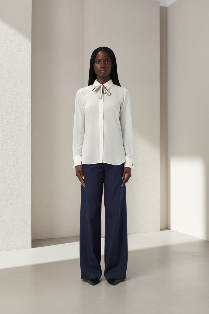 White blouse with a bow tie worn by a person on a white background