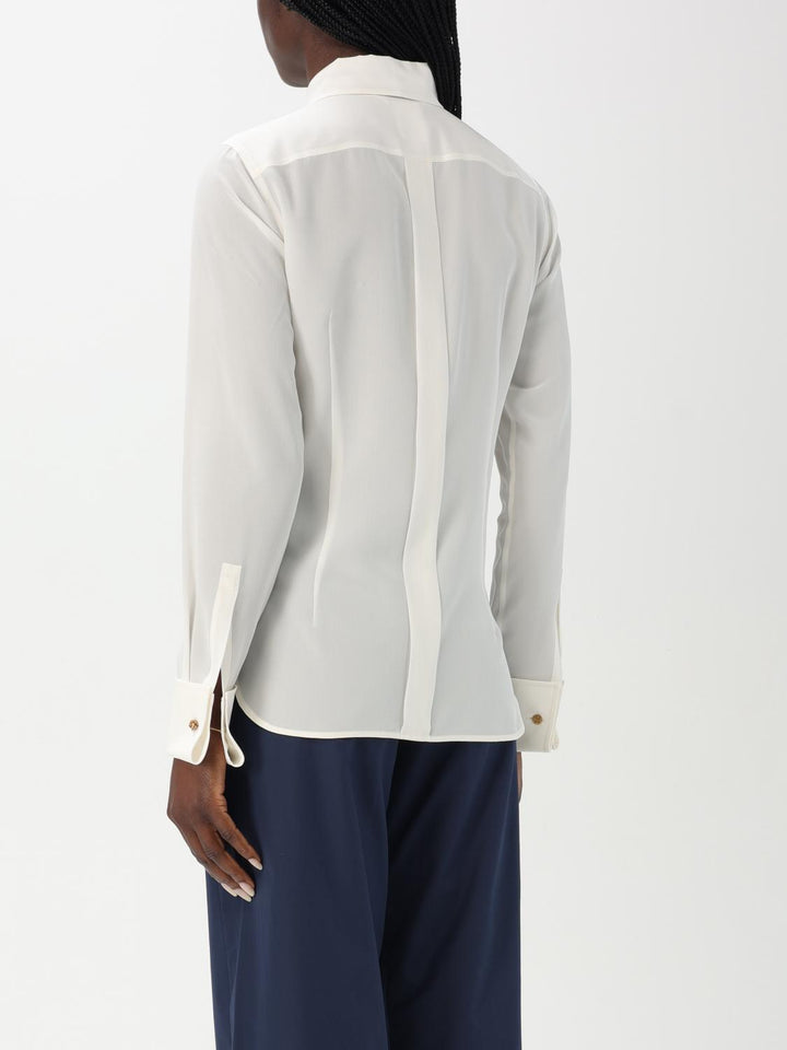 White blouse with sheer panels worn by a person on a white background