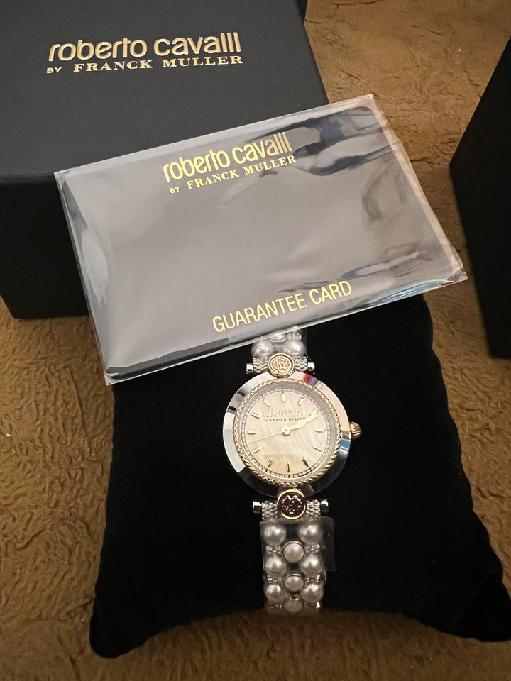 A Roberto Cavalli by Franck Walker watch with a pearl and crystal bracelet, displayed on a black velvet cushion next to its original packaging box and guarantee card.