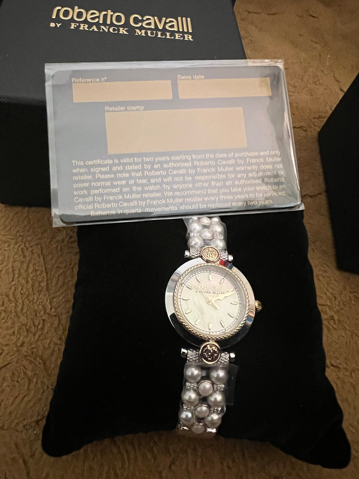 A Roberto Cavalli by Franck Muller watch displayed on a black cushion, with its certificate of authenticity in a clear plastic sleeve and part of the black branded box visible behind it.