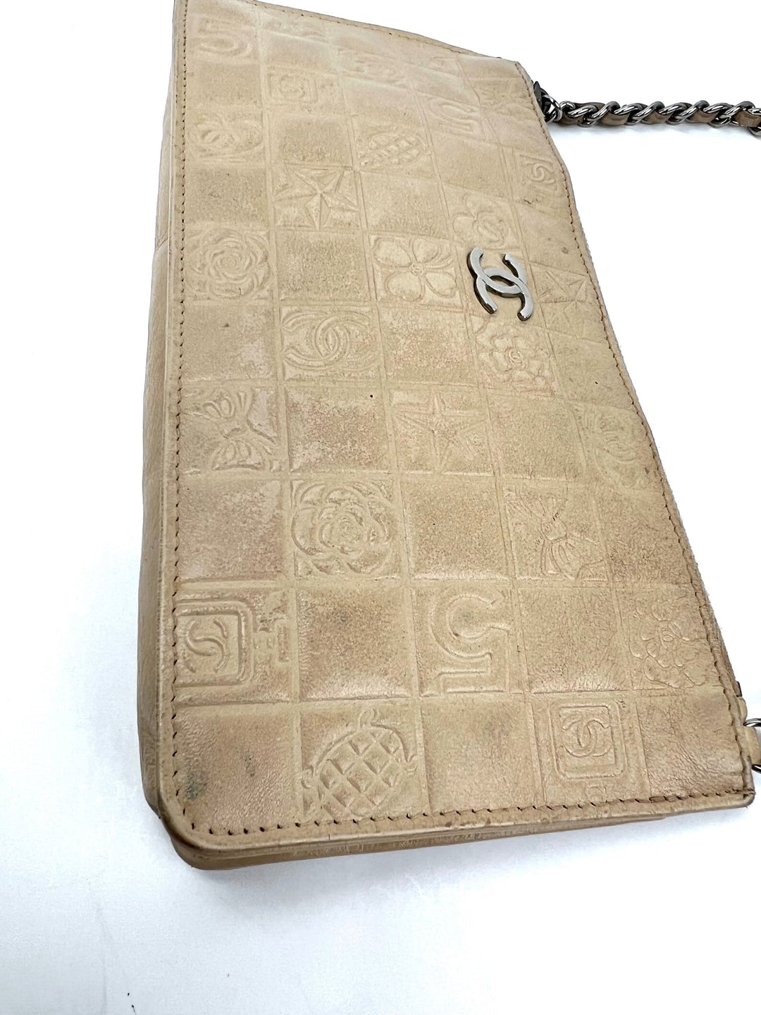 Beige handbag with embossed design and Chanel logo on a white background