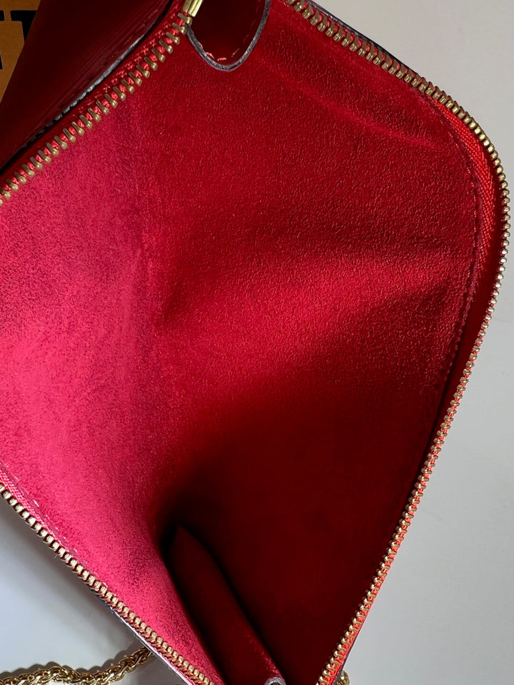 Close-up of a red handbag with gold zipper and chain detail.