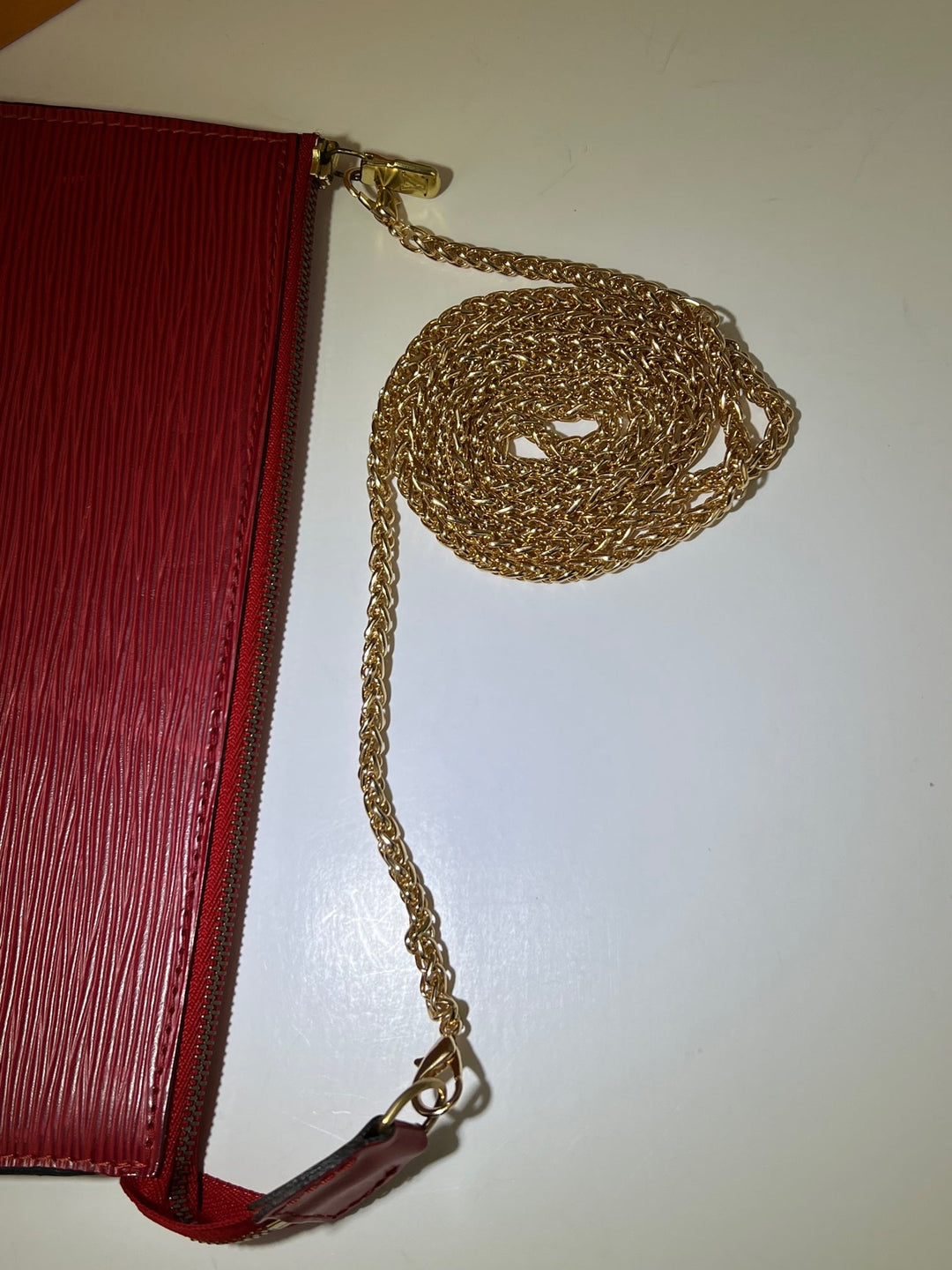 Red clutch with a gold chain on a white background