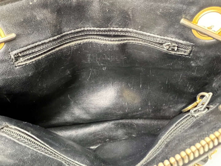 Close-up of a black leather bag with visible wear and tear.