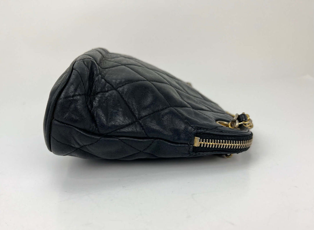 Black quilted handbag with gold zipper on a white background