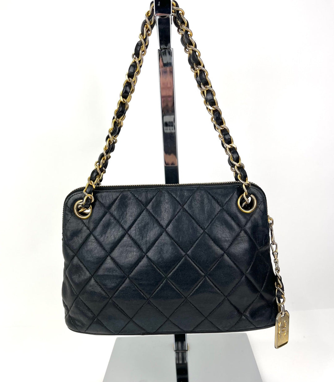 Black quilted handbag with gold chain strap on a white background