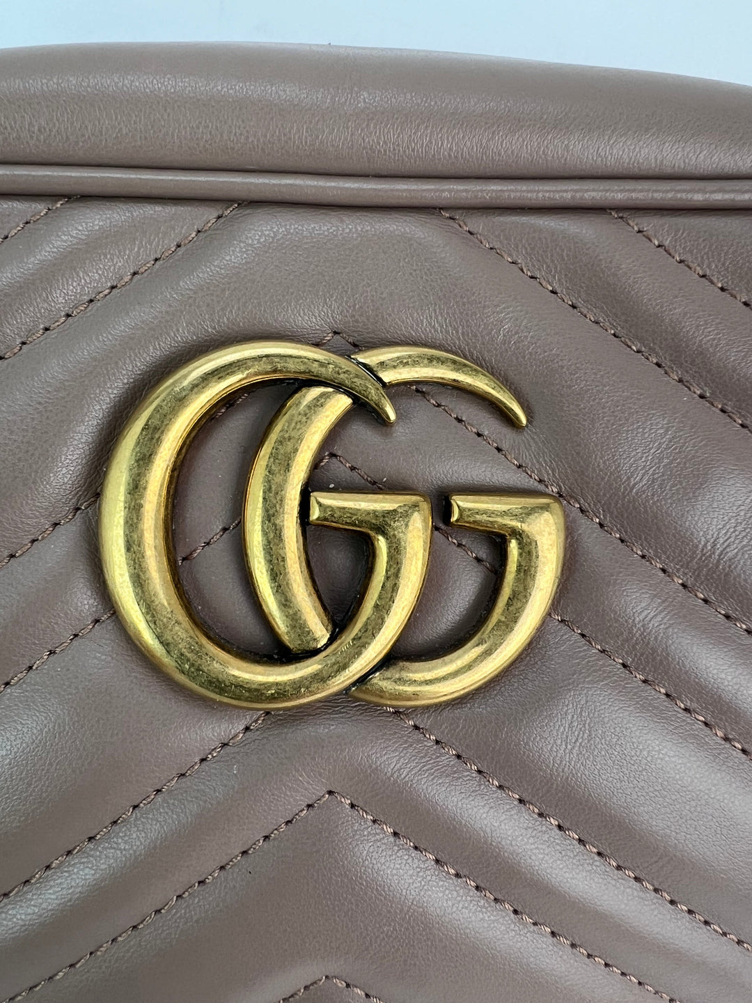 Close-up of a brown leather handbag with a gold Gucci logo.