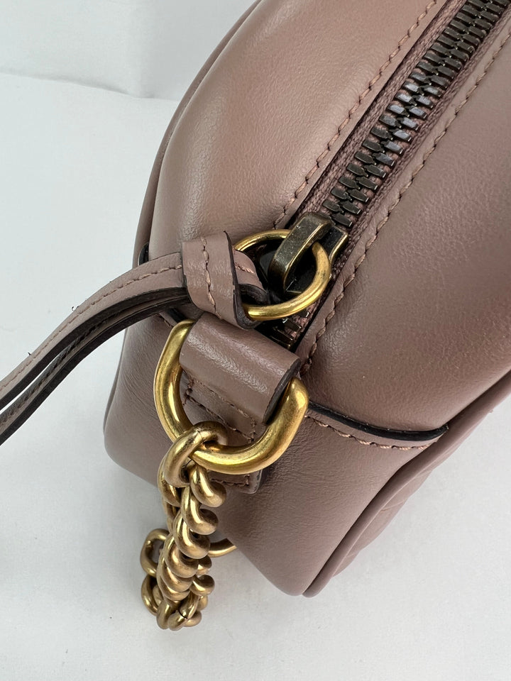 Close-up of a brown leather handbag with a gold chain detail on a white background
