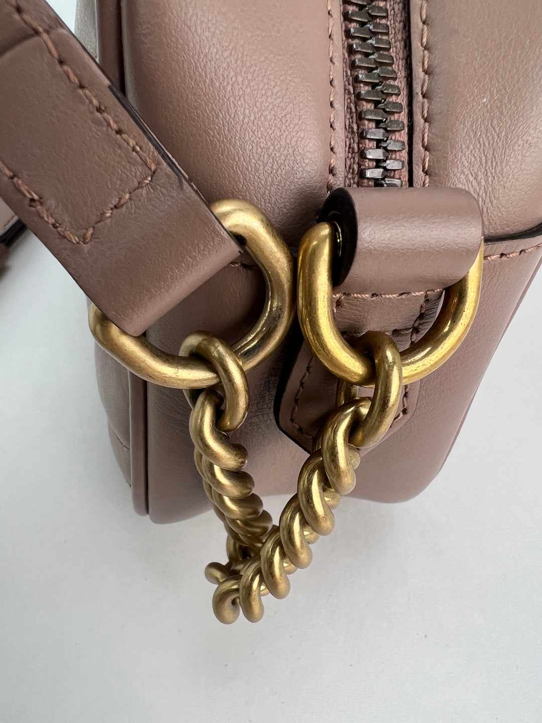 Close-up of a brown leather handbag with a gold chain detail on a white background