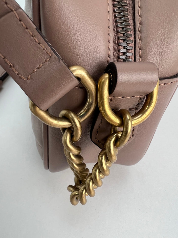 Close-up of a brown leather handbag with a gold chain detail on a white background