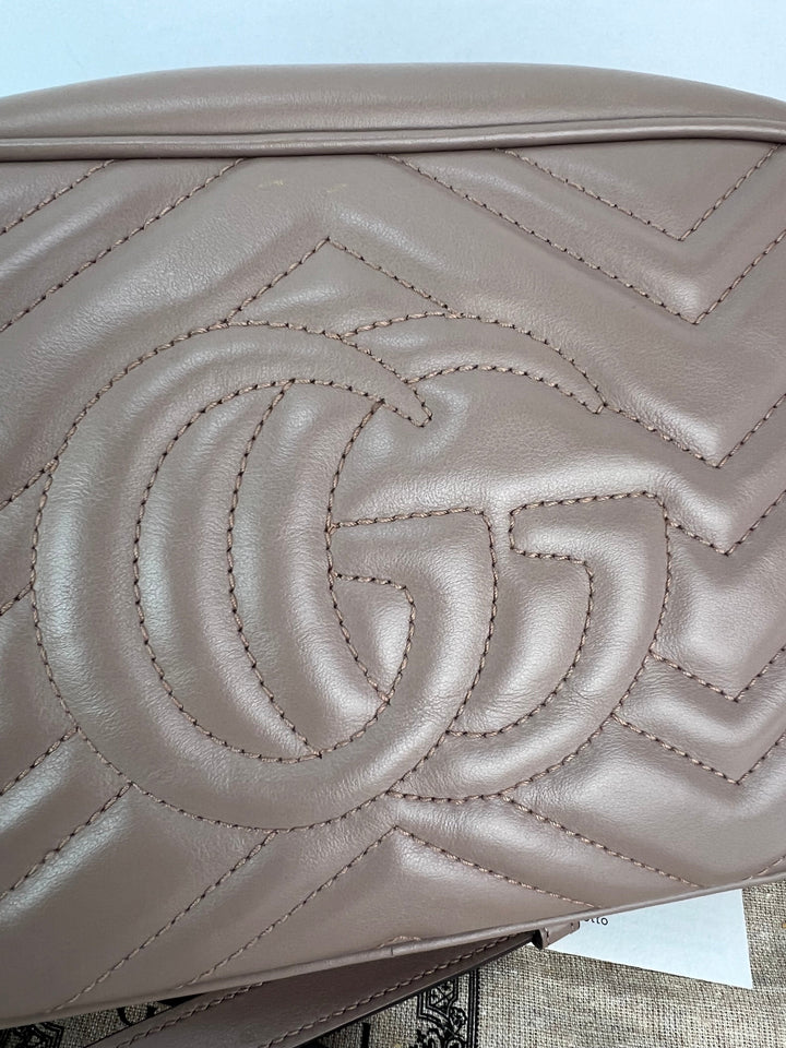 Close-up of a beige handbag with a prominent logo on a light blue background