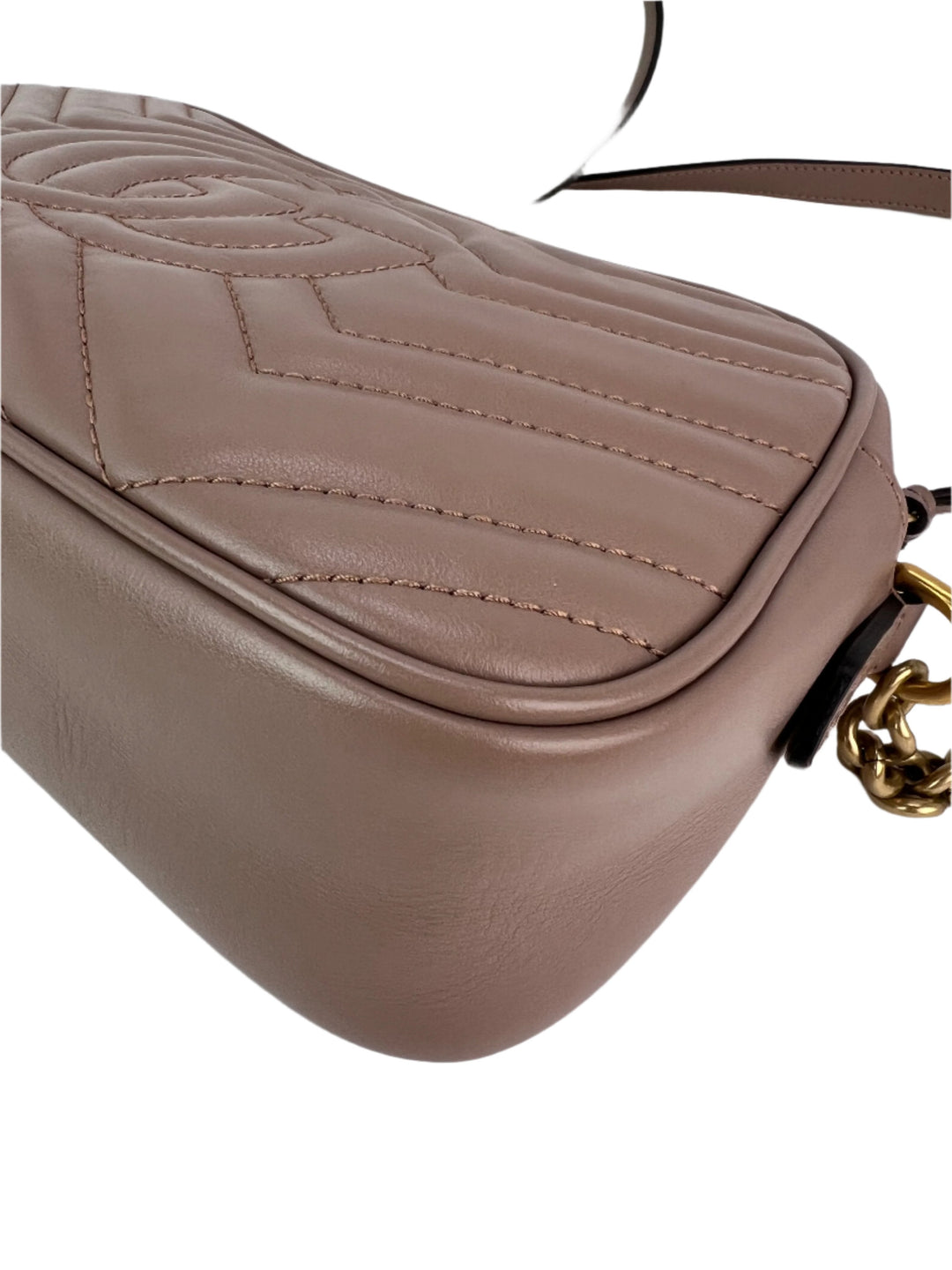 Close-up of a beige handbag with a gold chain detail on a white background