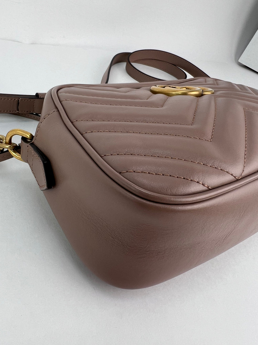 Brown leather handbag with gold accents on a light gray background