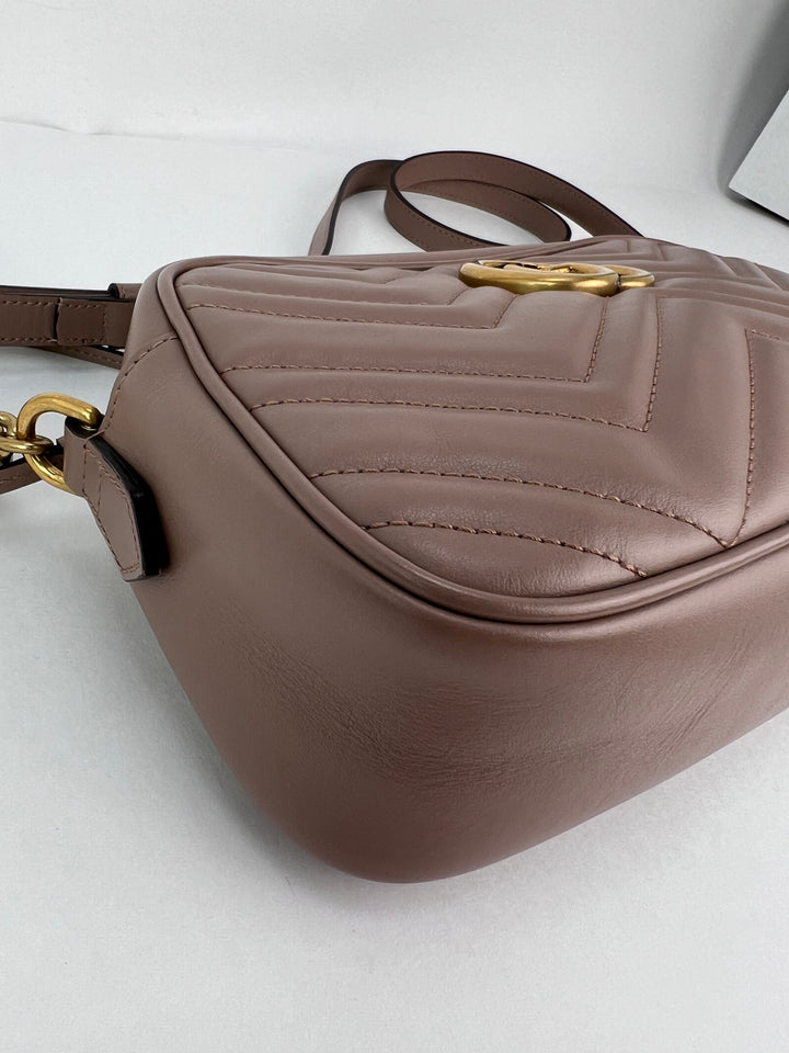 Brown leather handbag with gold accents on a light gray background