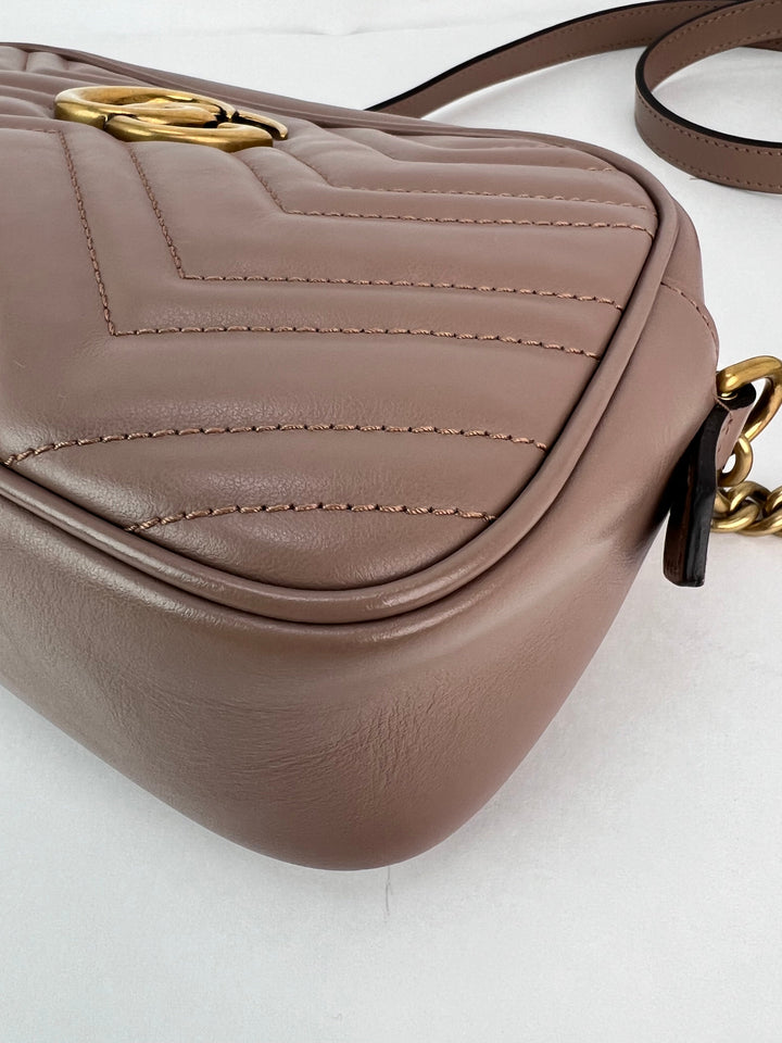 Brown leather handbag with gold chain detail on a white background