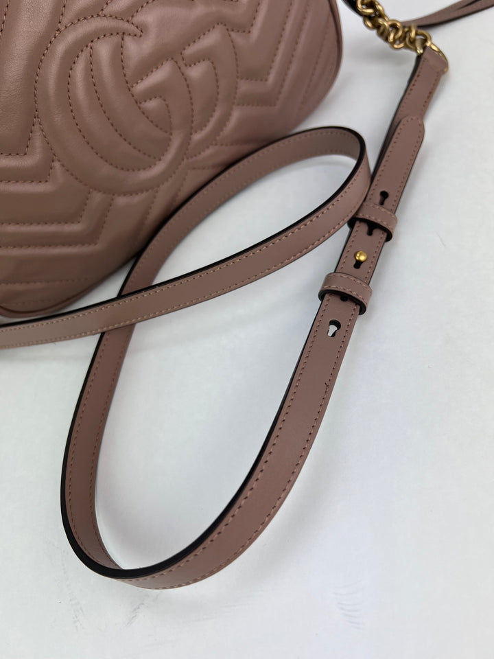 Brown leather handbag with embossed design and gold chain strap on a white background