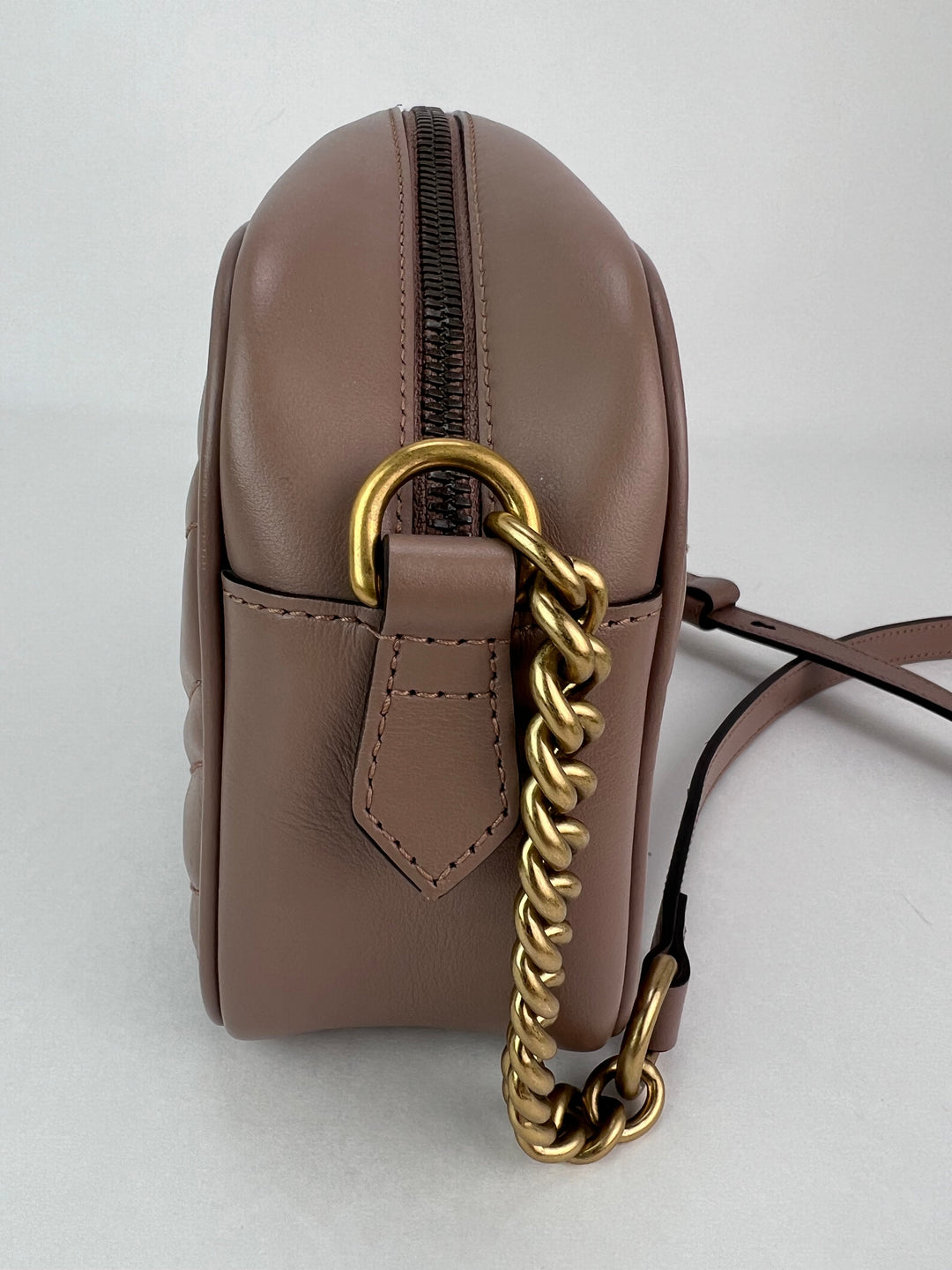 Brown leather handbag with gold chain detail on a white background