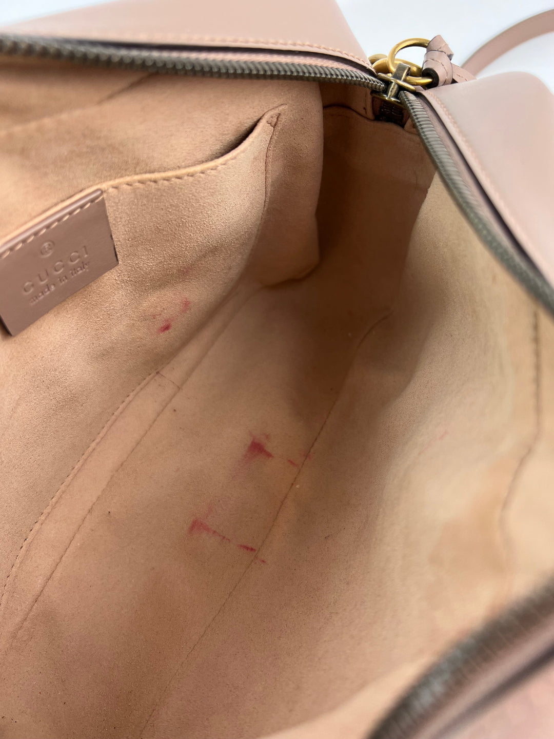 Close-up of a beige handbag with visible scuff marks on the interior.