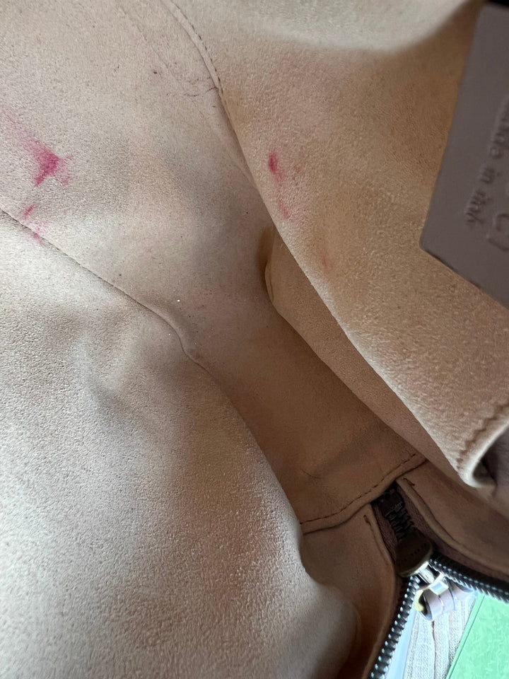 Close-up of a beige jacket with visible stains and a brand tag.