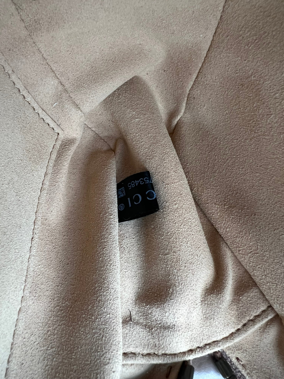 Close-up of beige fabric with a brand label on a neutral background