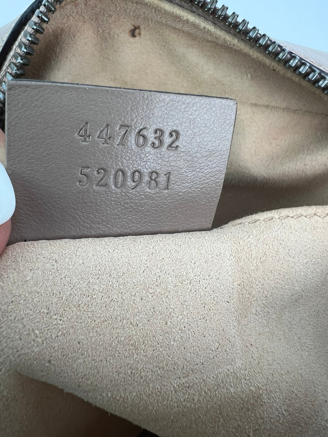 Close-up of a leather tag with numbers on a beige bag.