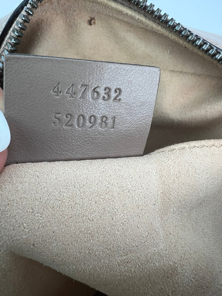 Close-up of a leather tag with numbers on a beige bag.