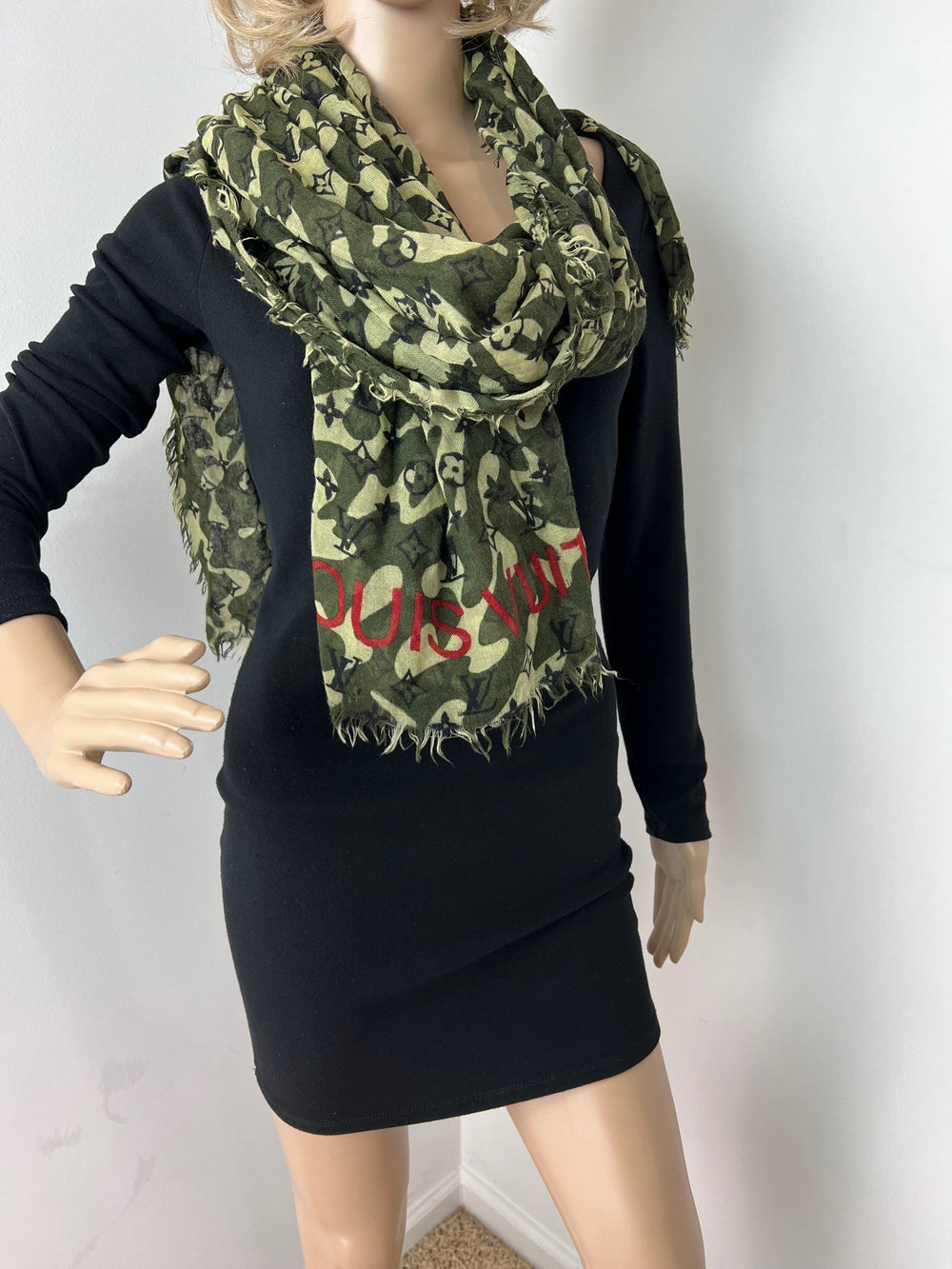 Mannequin wearing a black dress with a green camouflage scarf and red text.