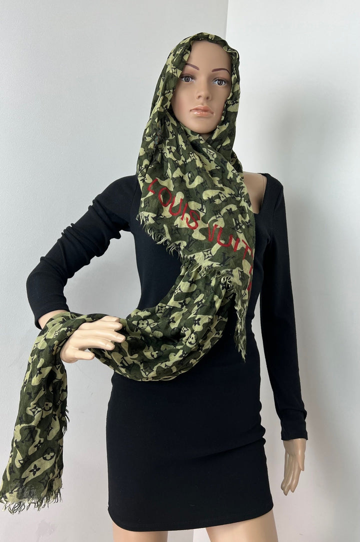 Mannequin wearing a black dress with a green camouflage scarf.