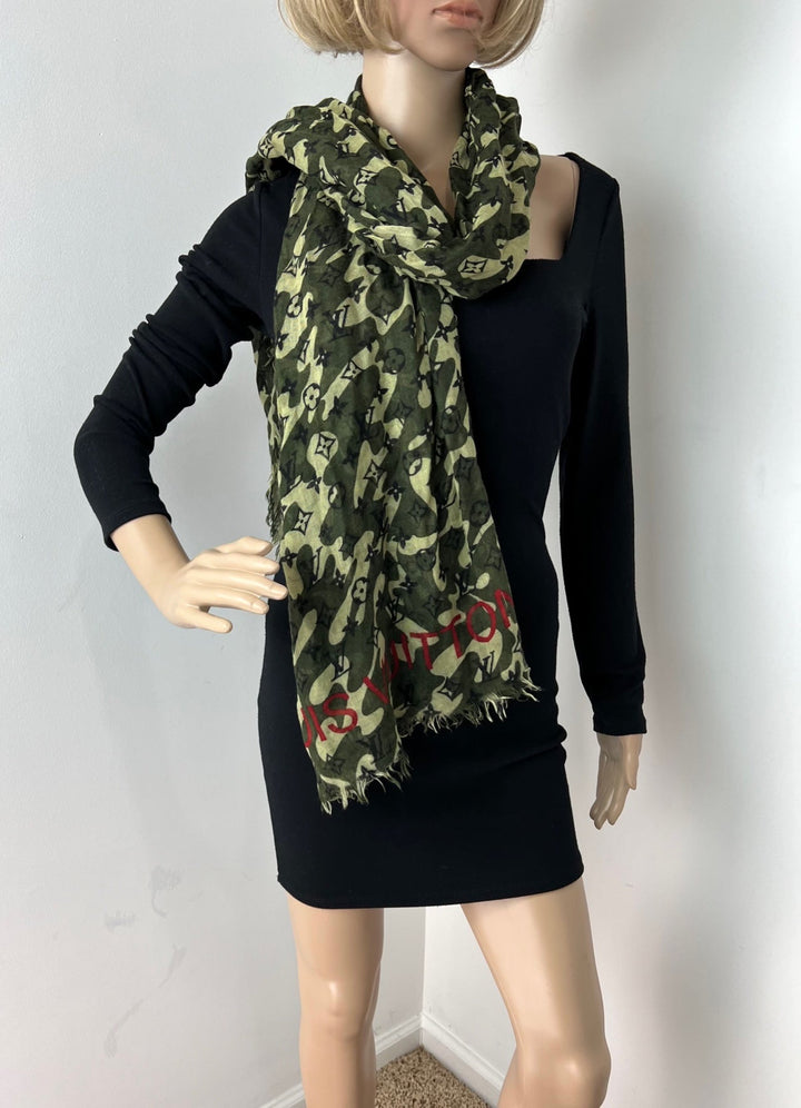 Mannequin wearing a black dress with a green camouflage-patterned scarf.
