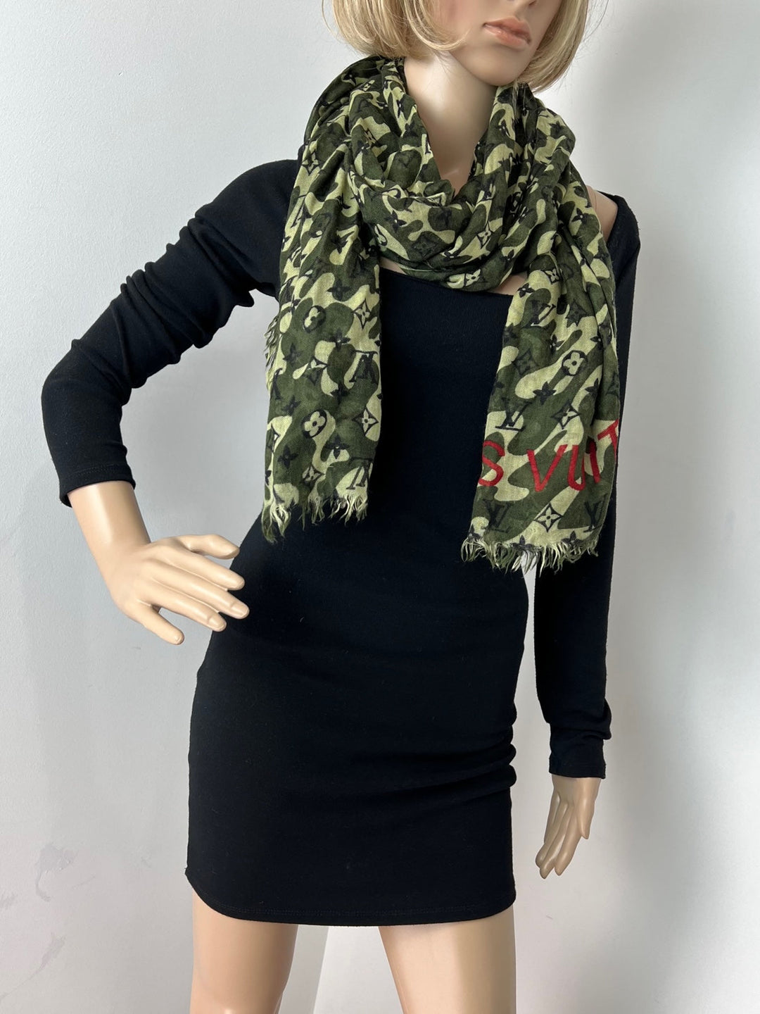 Mannequin wearing a black dress with a green camouflage-patterned scarf.