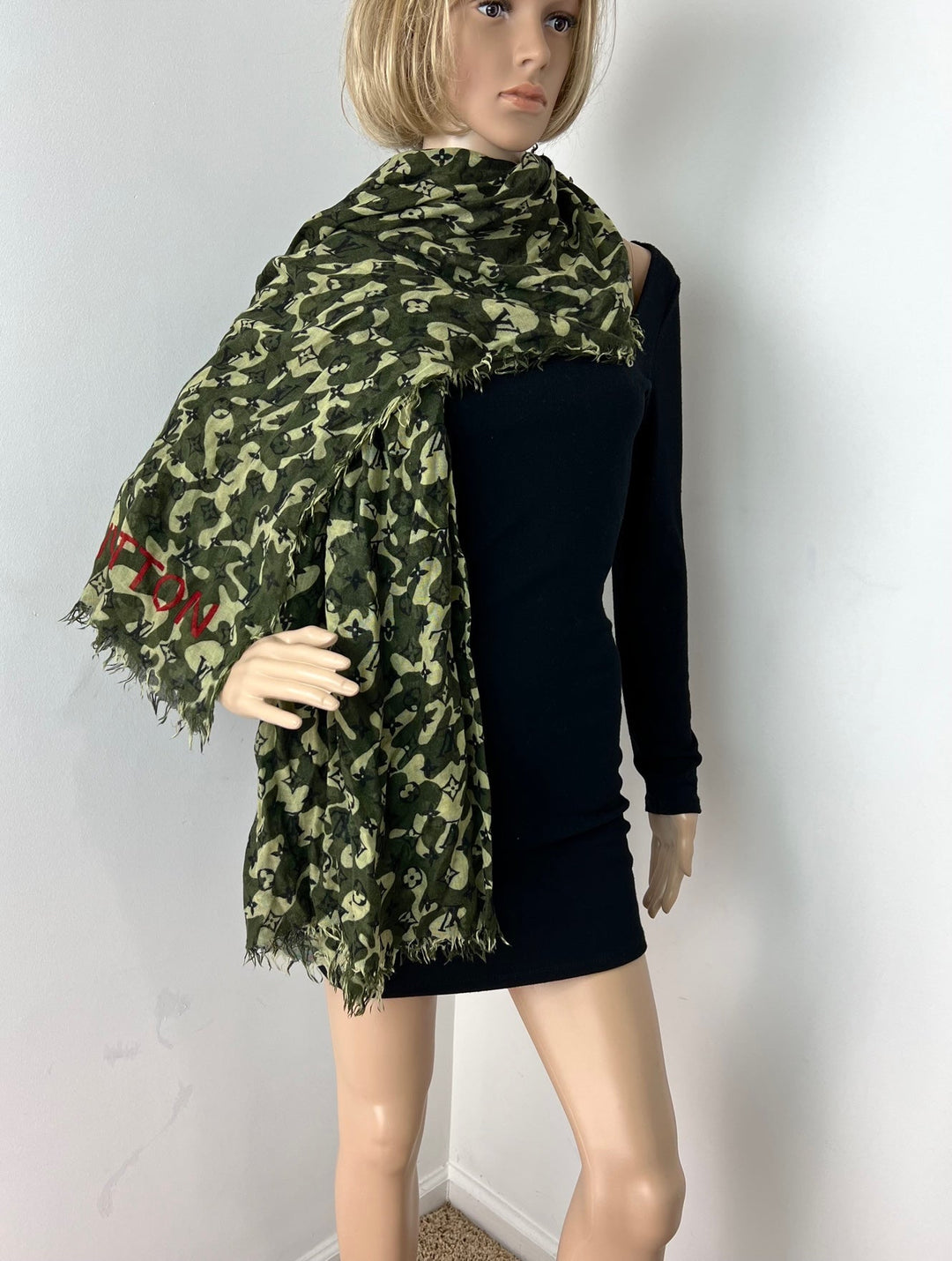 Person wearing a green camouflage scarf with red text on a white background
