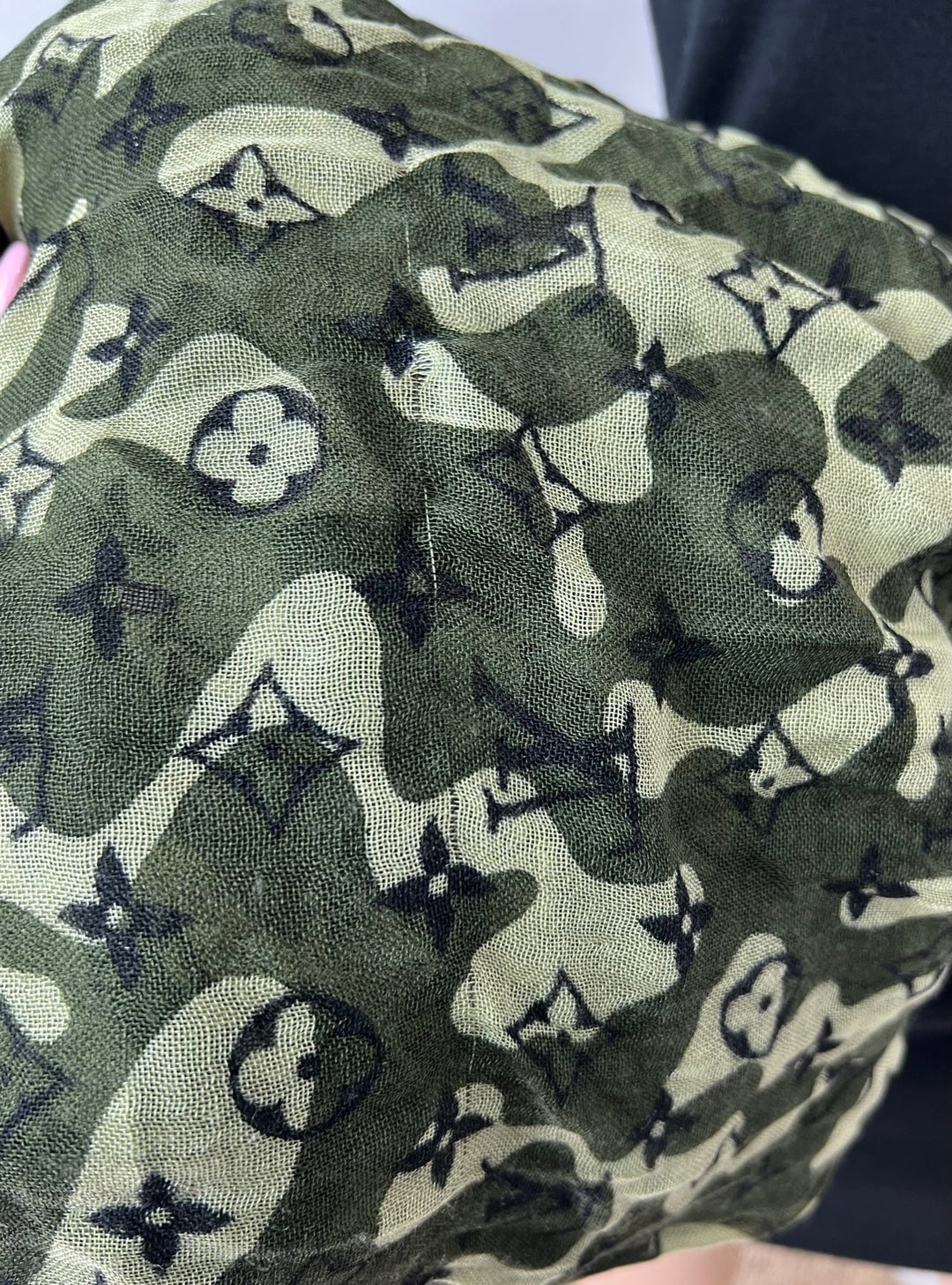 Green fabric with black and white pattern, possibly a Louis Vuitton design.